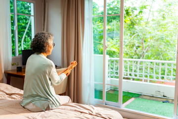 Asian senior mature woman sit on the bed suffering from finger wrist hand pain. Unhappy elderly feeling pain in joint and tendon from rheumatoid arthritis, osteoarthritis and peripheral neuropathy.
