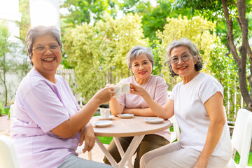 Group of Happy Asian senior mature women relax and enjoy indoor lifestyle meeting party together at home. Elderly retired woman friends drinking tea with talking together in the garden in summer day.