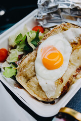 Fried egg in a pan with a salad of tomatoes and arugula.