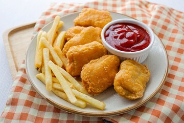Fried chicken nuggets with french fries and tomato sauce in a ceramic plate on white background table, top view food table