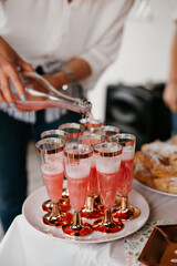 A young girl pouring pink champagne into glasses. The photo is bright and aesthetic.