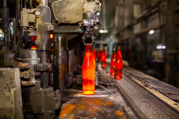 Glass factory, production of glass containers. Molten glass is blown into molds. Robotics in industry. Modern technologies, robotic machines produce products. Technological work at the plant.