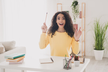 Photo portrait of teenager young wavy hair american surprised girl in yellow shirt sitting workplace doing homework for college indoors