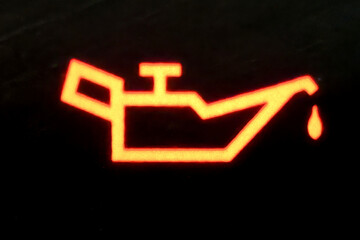 An extremely close-up picture of an engine oil light signal glowing on the dashboard.