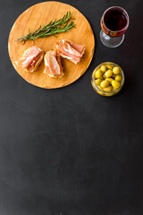 Spanish meal. Prosciutto ham on wooden board and glass of wine