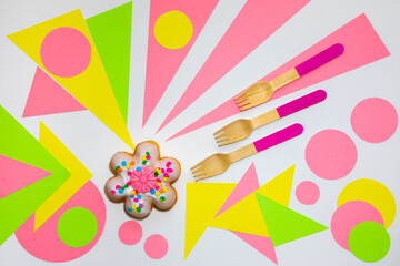 Flower shaped donut with wooden spoons on a multicolored grafic background