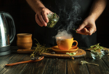 Herbalist prepares medicinal tea with mint and dry herbs in orange mug. Concept of traditional medicine at home.