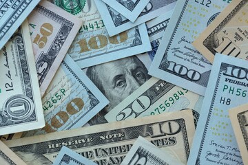 Many dollar bills with different nominations lies in big pile