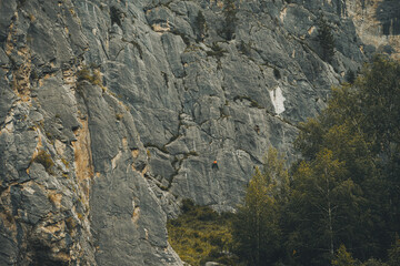 Majestic rock formations tower over a lush landscape with trees, illuminated by the warm glow of the late afternoon sun in the Altai Mountains