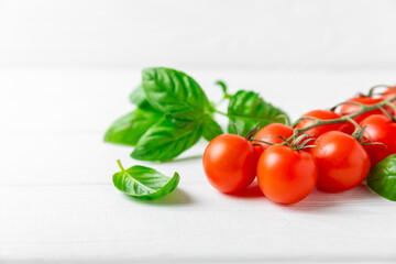 Fresh cherry tomatoes and fresh green basil on a textured background. Tomato sauce. Vegan. Ingredients for salad. Organic food. Place for text. Copy space.