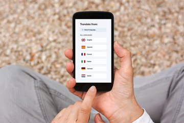 Hands holding smartphone with language translator app concept on screen. Flat lay