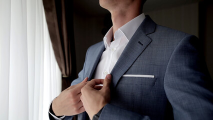 Close-up of a stylish businessman adjusting his suit jacket. Ideal for showcasing professionalism, confidence, and sophisticated business attire.