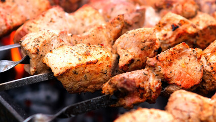 Close-up of sizzling kebabs on skewers grilling over an open flame. Perfect for showcasing outdoor cooking and barbecue flavors.