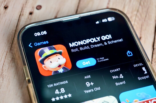 Jakarta, Indonesia - August 22th, 2024 - Monopoly Go! game mobile application on phone screen isolated on horizontal wooden surface background.