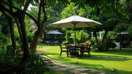 chairs with coffee table and umbrella near green grass lawn