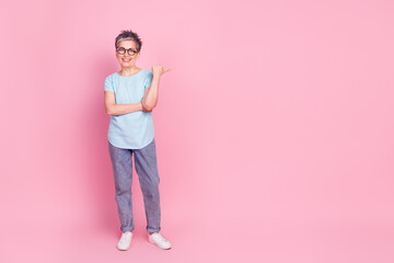 Full body portrait of nice aged lady indicate finger empty space isolated on pink color background