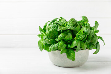 Green basil leaves on a textured wooden background. Kitchen herbs, spices. Fresh green organic basil. Vegan. Greens for salad. Place for text. Copy space.