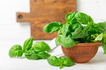 Green basil leaves on a textured wooden background. Kitchen herbs, spices. Fresh green organic basil. Vegan. Greens for salad. Place for text. Copy space.