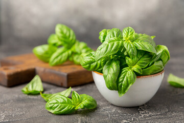 Green basil leaves on a textured wooden background. Kitchen herbs, spices. Fresh green organic basil. Vegan. Greens for salad. Place for text. Copy space.
