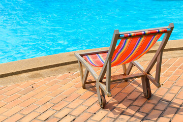 Colorful beach lounge chair or sun deckchair with swimming pool side view on beach for concept of vacation beach and sea in summer holiday resort.