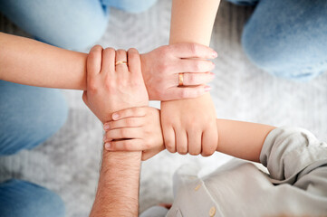 Top view of family hands holding each others wrists in circle, creating chain of support or unity....