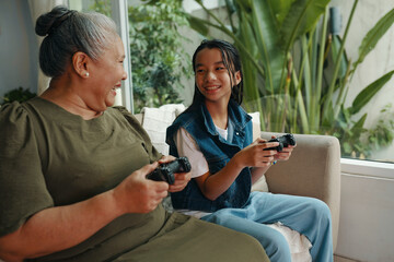 Teenage girl playing console with her granny at home