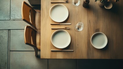 Wooden table set for dinner with white plates.