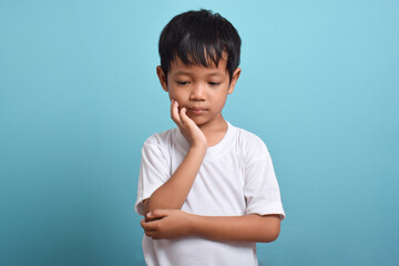 Little Asian boy suffering from toothache. toothache emotions large inflated cheek. A sad child with a toothache. Dental problem.