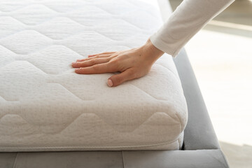 Woman hand testing white and new orthopedic mattress on firmness