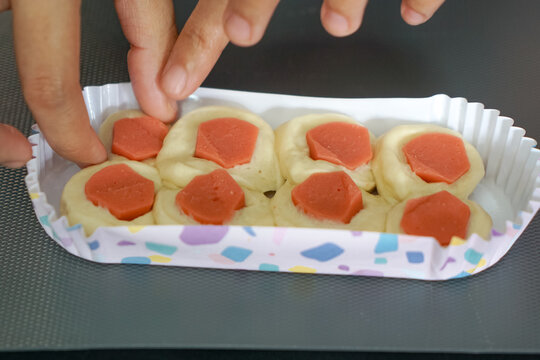 Sausage bun placed in a long paper baking cup.  Bread making process. Close up.