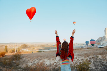 joyful woman holding heartshaped balloon with arms raised in celebration