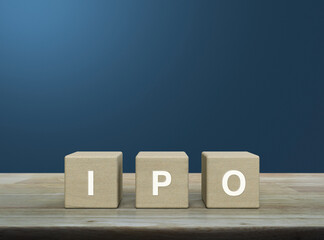 IPO acronym on wood block cubes on wooden table over light blue wall, Initial public offering...