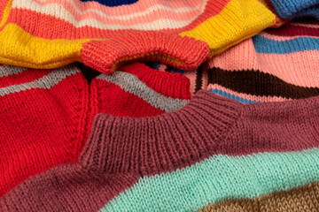 Multicolored children's hand-knitted sweaters. Close-up.