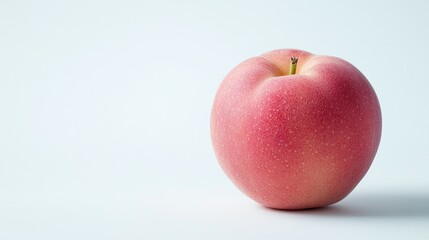A single, fresh Japanese peach with its vibrant skin, isolated on a clean white background. Copy space provided.