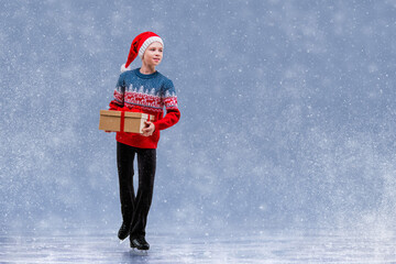 Boy figure skater in Santa Claus hat skating on ice. © Maria Moroz