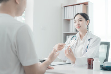 Asian female nurse talking and asking about symptoms of young male patient using blood pressure monitor to measure blood pressure level Medical examination result during consultation