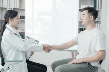Fototapeta premium Asian female nurse talking and asking about symptoms of young male patient using blood pressure monitor to measure blood pressure level Medical examination result during consultation