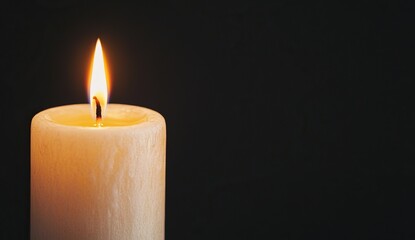 A close-up view of a burning white candle against a black background