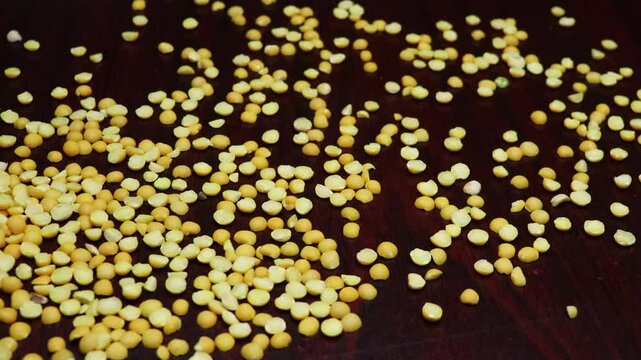 Dried yellow peas scatter on black board 4k footage. Pigeon peas, Arhar legume disperse. Slow motion. 
