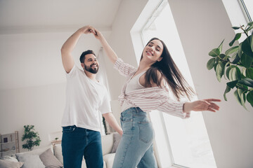 Photo of two idyllic partners hold arms dancing modern bright interior weekend flat indoors