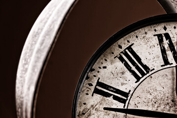 Broken old analog clock with glass and metal frame on wooden table, broken structure