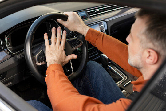 Man driving and holding steering wheel, pressing horn, view from outside