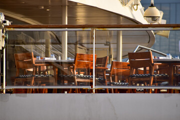 Outdoor seats on passenger ship deck with the calm seascape. Cruise ship deck. Wooden promenade deck on a luxury cruise liner. Ocean in background.