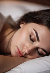 Fototapeta premium Brunette girl with long eyelashes peacefully sleeping on bed, showcasing serene moment during early morning hours. Brunette woman sleeps soundly on pillow. Tranquility and calmness. AI art. Morning