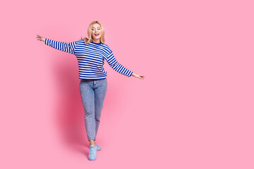 Full body photo of attractive mature woman walk tightrope keep balance dressed stylish striped clothes isolated on pink color background