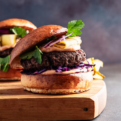 Beef burgers with pickles and red onion on cutting board