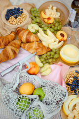 Summer picnic with fresh fruit and croissants in the garden. Natyarmort croissant, fruit, melon, grape, apple