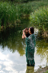 Beautiful  brunette extra long braided hair girl in Indian traditional dress posing near river . Portrait of young attractive stylish woman in sari on  green nature background.