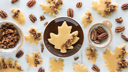 Homemade maple pecan leaf shortbread cookies scattered about with pecans.