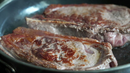 Partially cooked steaks in a pan, starting to brown, close-up view, home cooking, delicious meal in progress, fresh beef, culinary preparation, sizzling sound, detailed kitchen scene